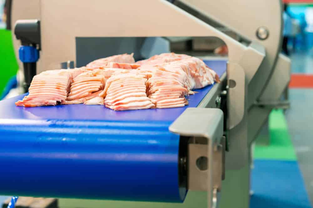 Sliced pork on conveyor belt of Grasselli machine