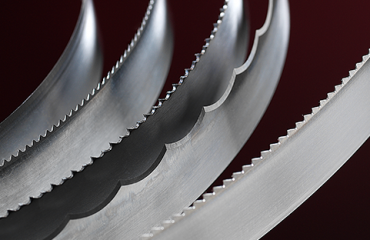 Various Simmons' foam cutting blades curve and catch the light against a dark background.