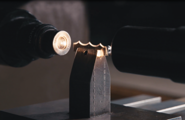 A piece of a Scallop bandknife blade is inspected for flaws using advanced machinery.