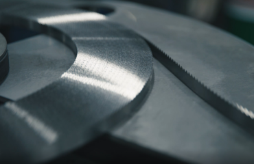 A Simmons Butcher bandsaw blade is slowly uncoiled and fed into a machine.