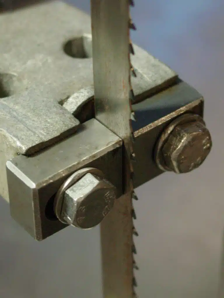 A bandsaw blade runs through steel guides.